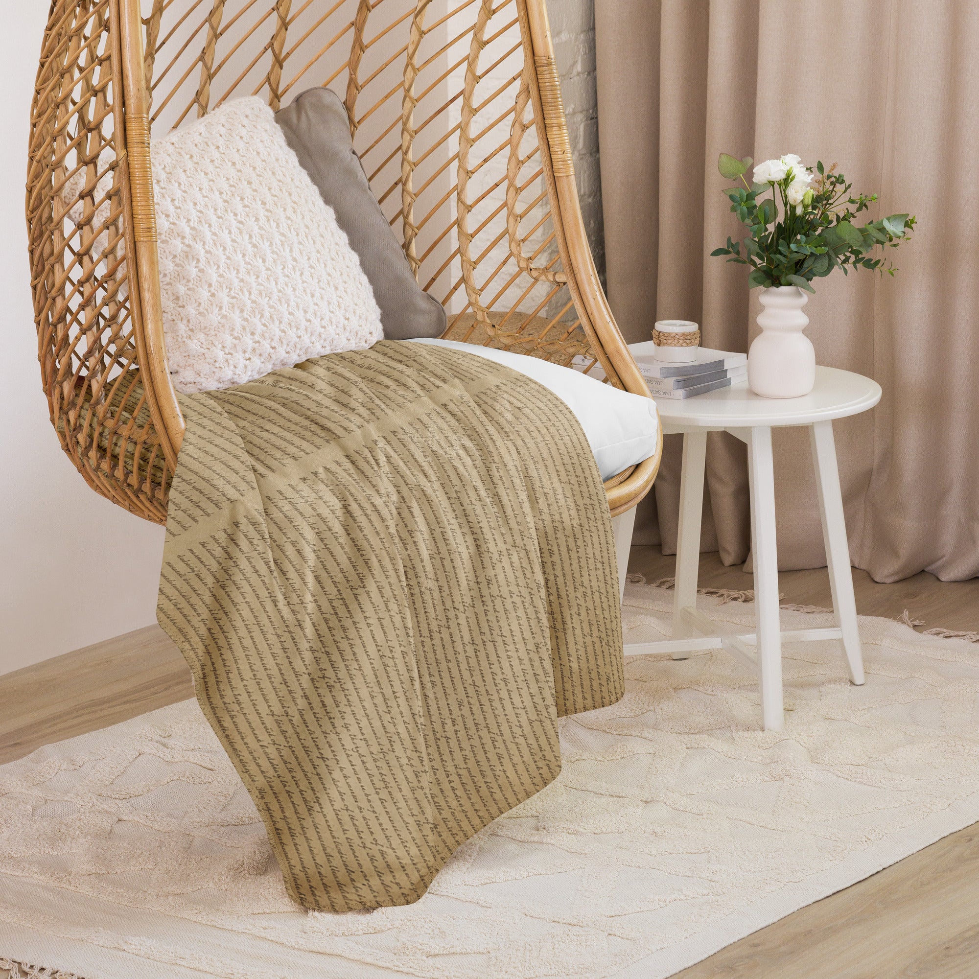 Luxury Sherpa Throw Blanket draped over a wicker hanging chair with textured pillows, next to a white round side table holding a vase with flowers in a cozy, elegant living space.