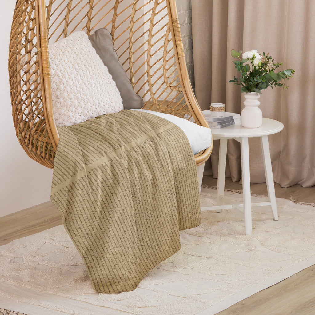 Luxury Sherpa Throw Blanket draped over a woven hanging chair with white cushion, next to a white side table holding a small vase of flowers and decorative items in a cozy room setting.